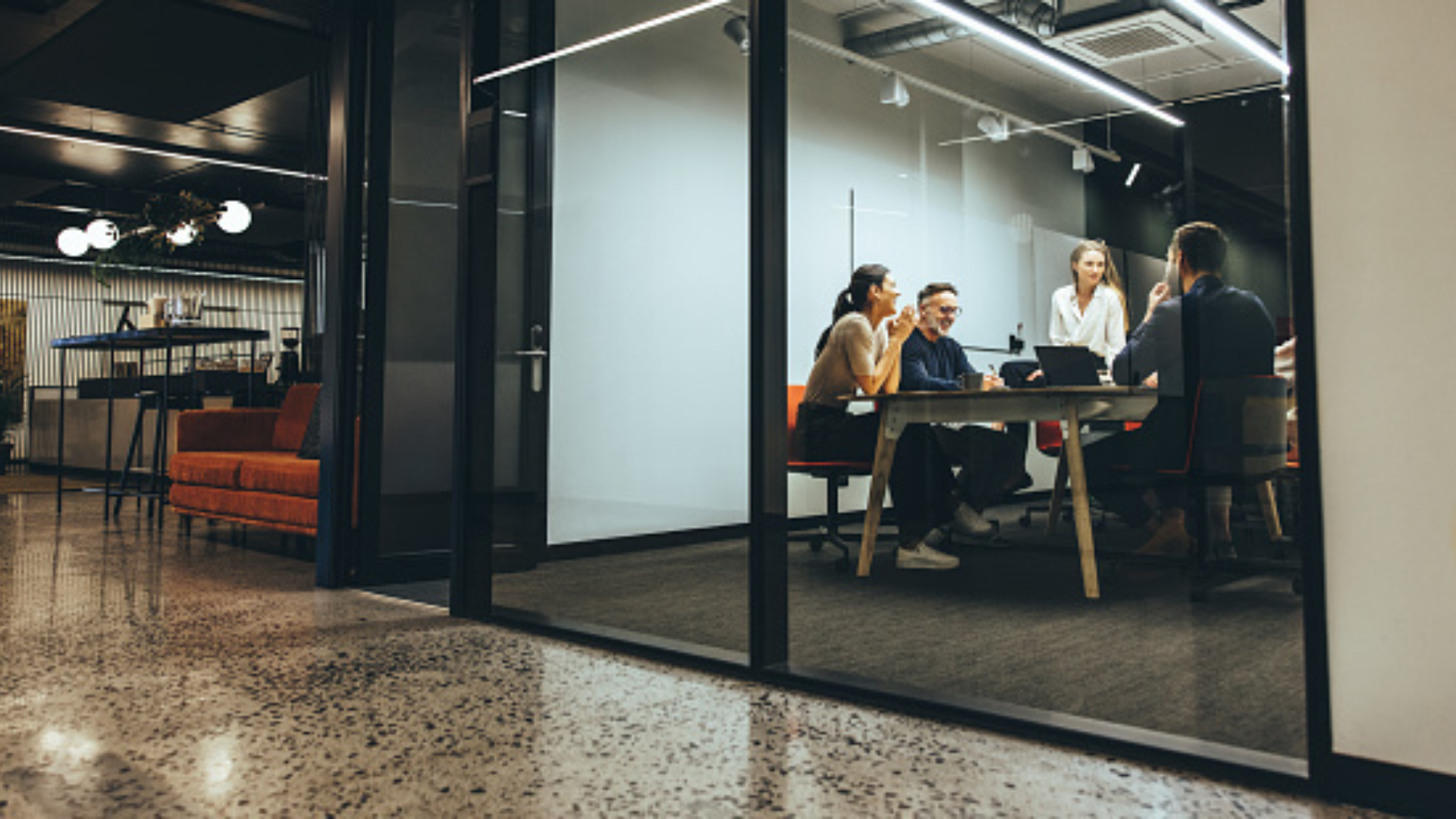 Modern office interior featuring a clear glass meeting room and open workspace