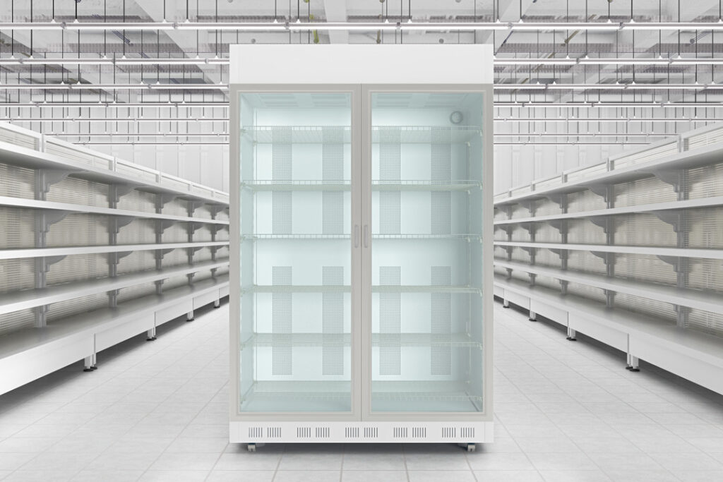 An empty, brightly lit aisle with a large, glass-door refrigerator centered. Metallic shelves line the space.