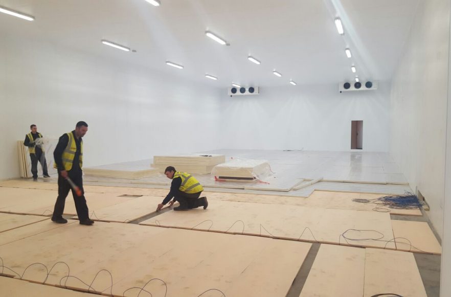Workers installing insulated flooring panels